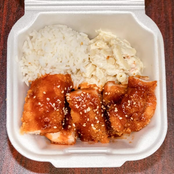 Hawaiian chicken katsu plate lunch with rice and macaroni salad in a white takeout container.