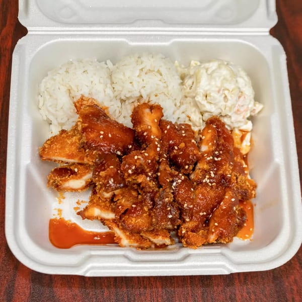Hawaiian plate lunch with crispy chicken, white rice, and macaroni salad in a takeout container.