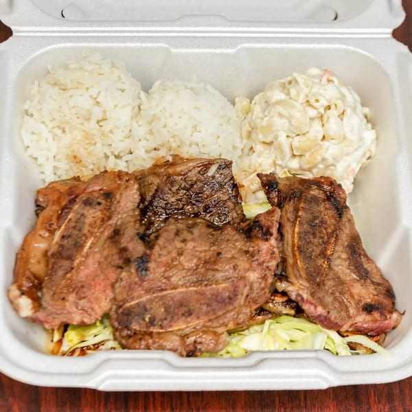 F's Hawaiian Food kalbi short ribs, rice, and macaroni salad in a white takeout container.